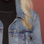 Woman with blonde hair, denim jacket, and black turtle neck.