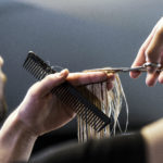 Stylist cutting a client's hair with scissors and a comb
