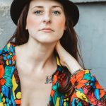 Pickthorn hair stylist Chelsey Pickthorn posing in a black hat and colorful floral blouse