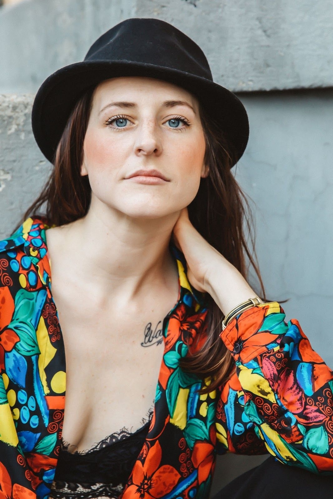 Pickthorn hair stylist Chelsey Pickthorn posing in a black hat and colorful floral blouse