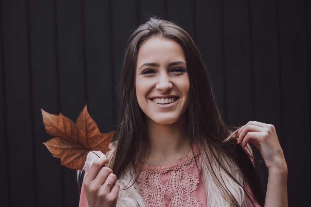 girl smiling while holding a leaf