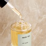 Custom hair oil in front of a marbled blush background