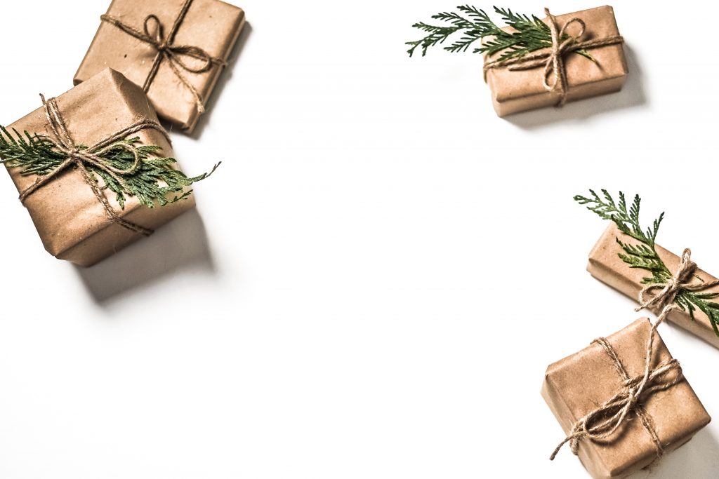 image of gift boxes wrapped in plain brown wrapping paper with twine ribbon and a pine leaf