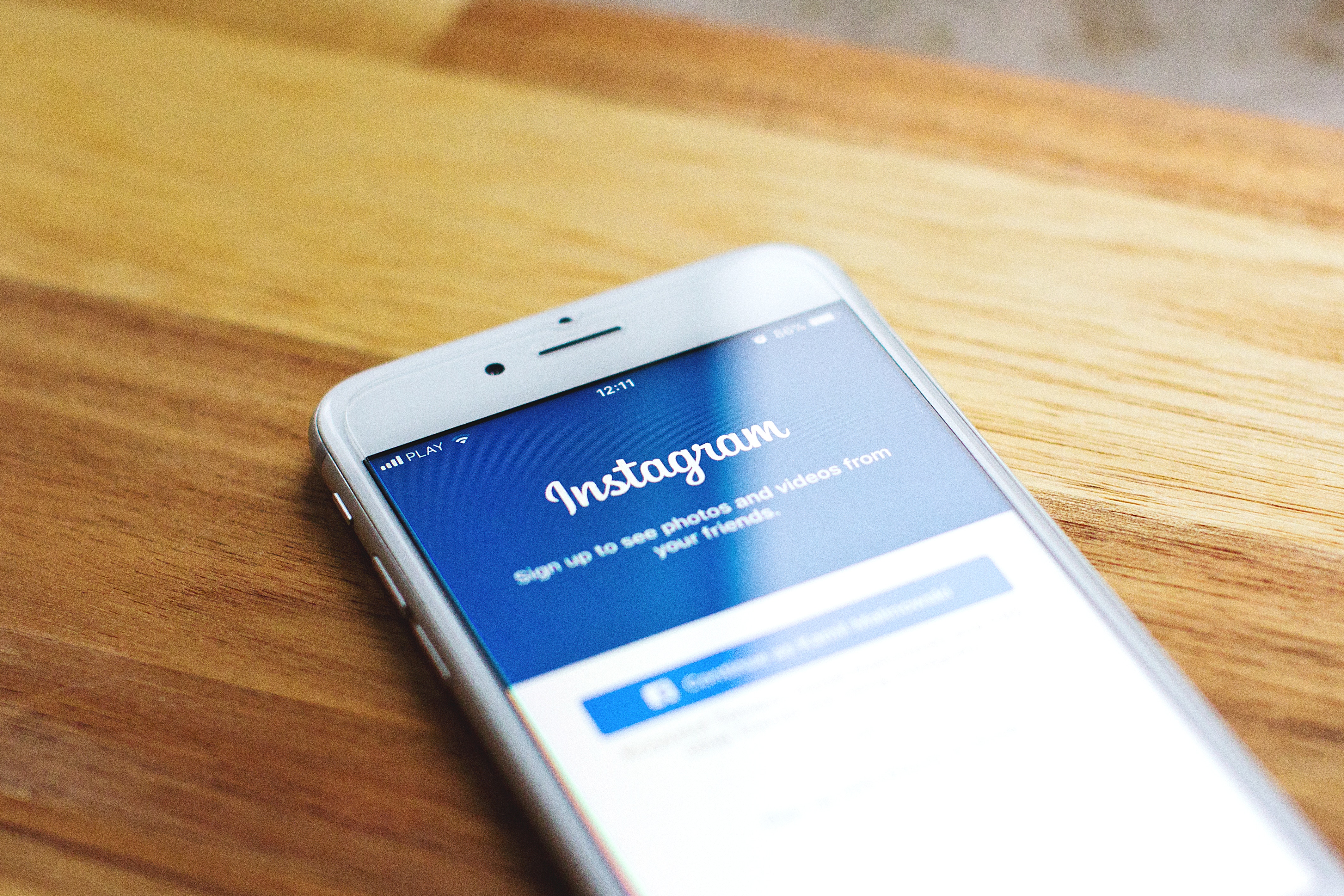 Image of a white iPhone on a wooden table with the Instagram app sign in page open
