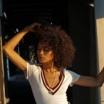 Woman with curly hair in sunlight touching her hair