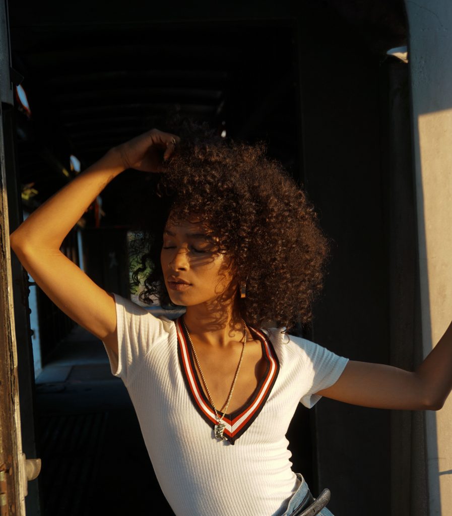 Woman with curly hair in sunlight touching her hair