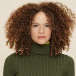 woman with curly hair and a turtleneck sweater
