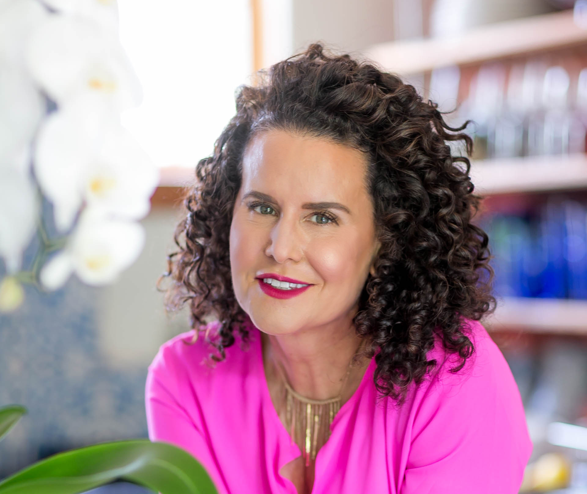 naturally curly founder michelle breyer poses with her dark, curly hair in a hot pink top
