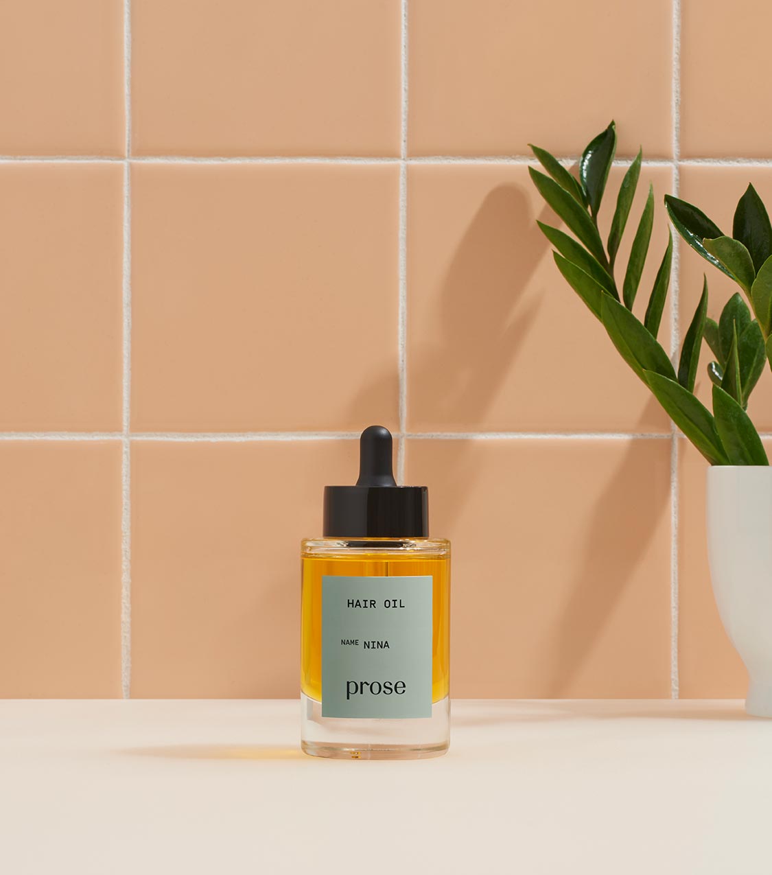 prose custom hair oil against a peach, tile backdrop