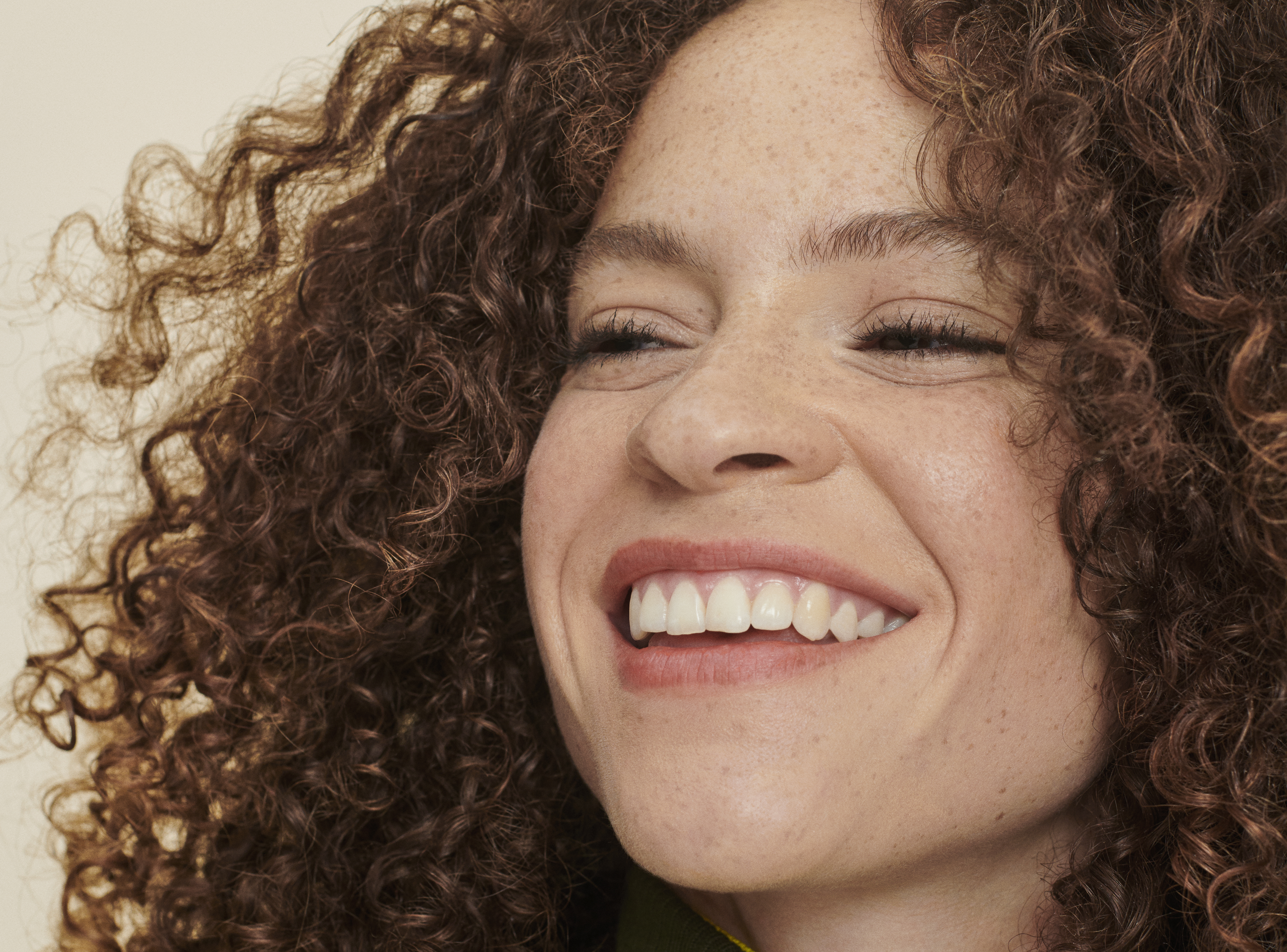 woman with brown, curly hair smiles
