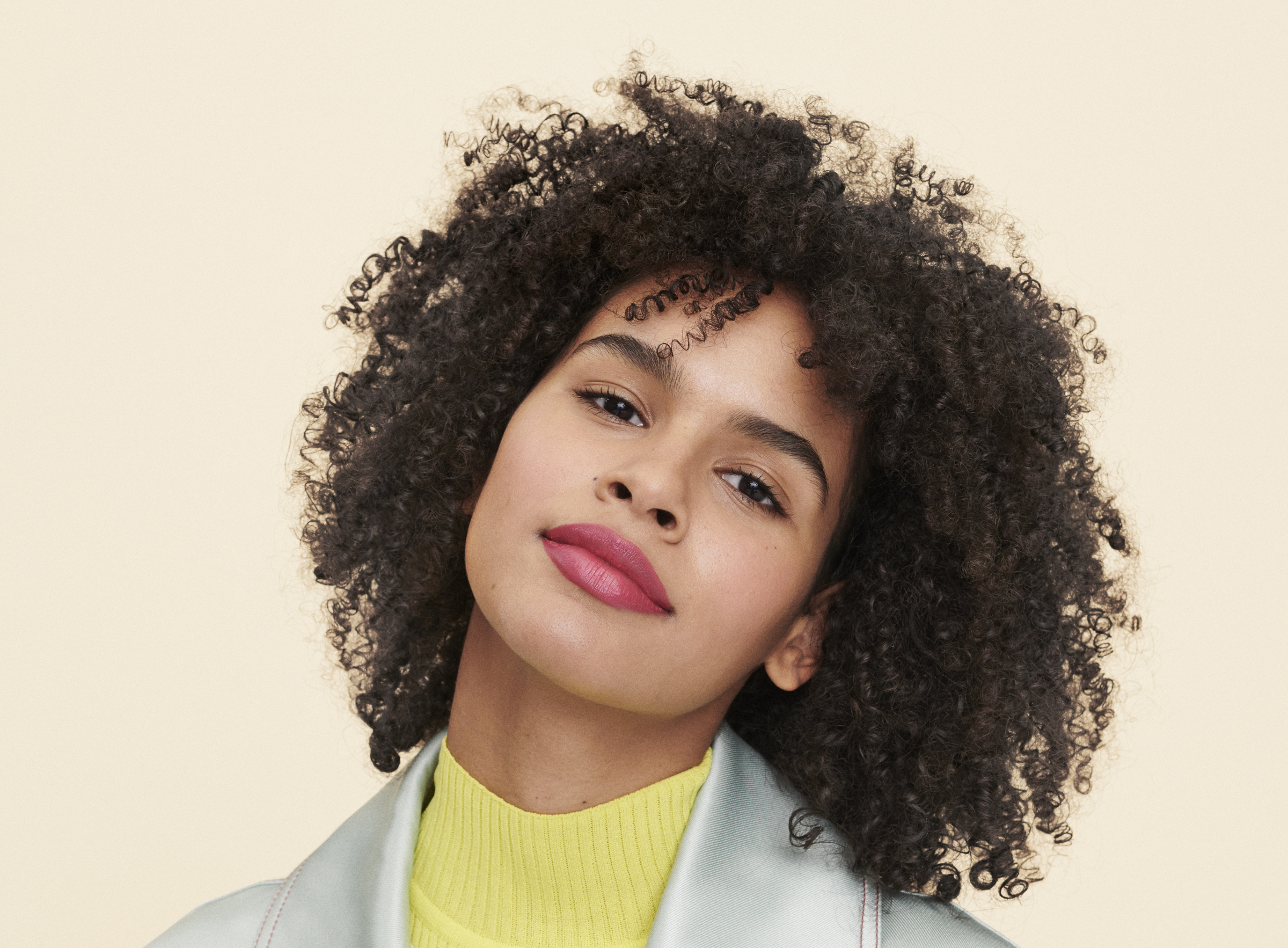 woman with shoulder length dark curly hair softly smiles