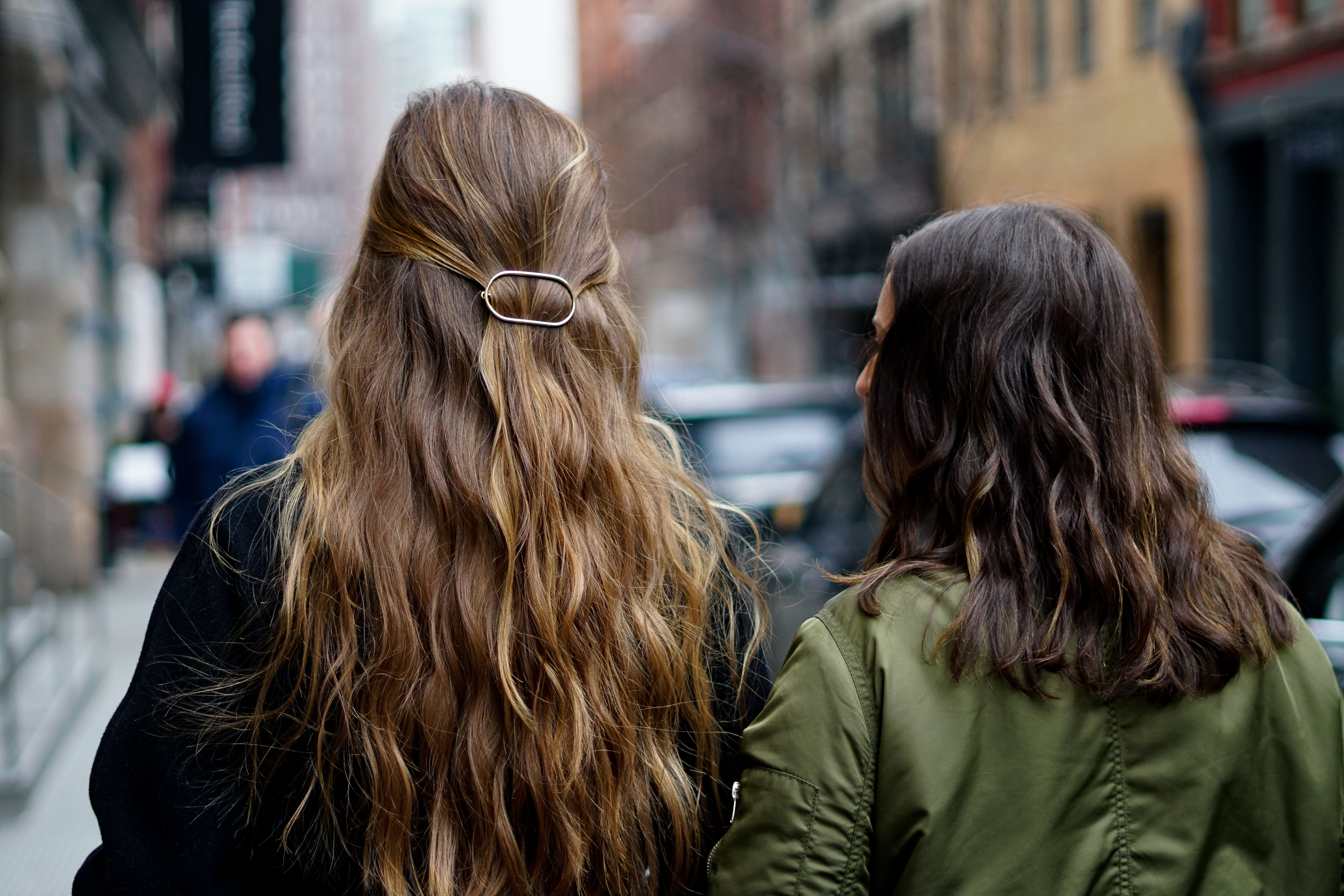 two women with light and dark brown hair walk down a new york city street