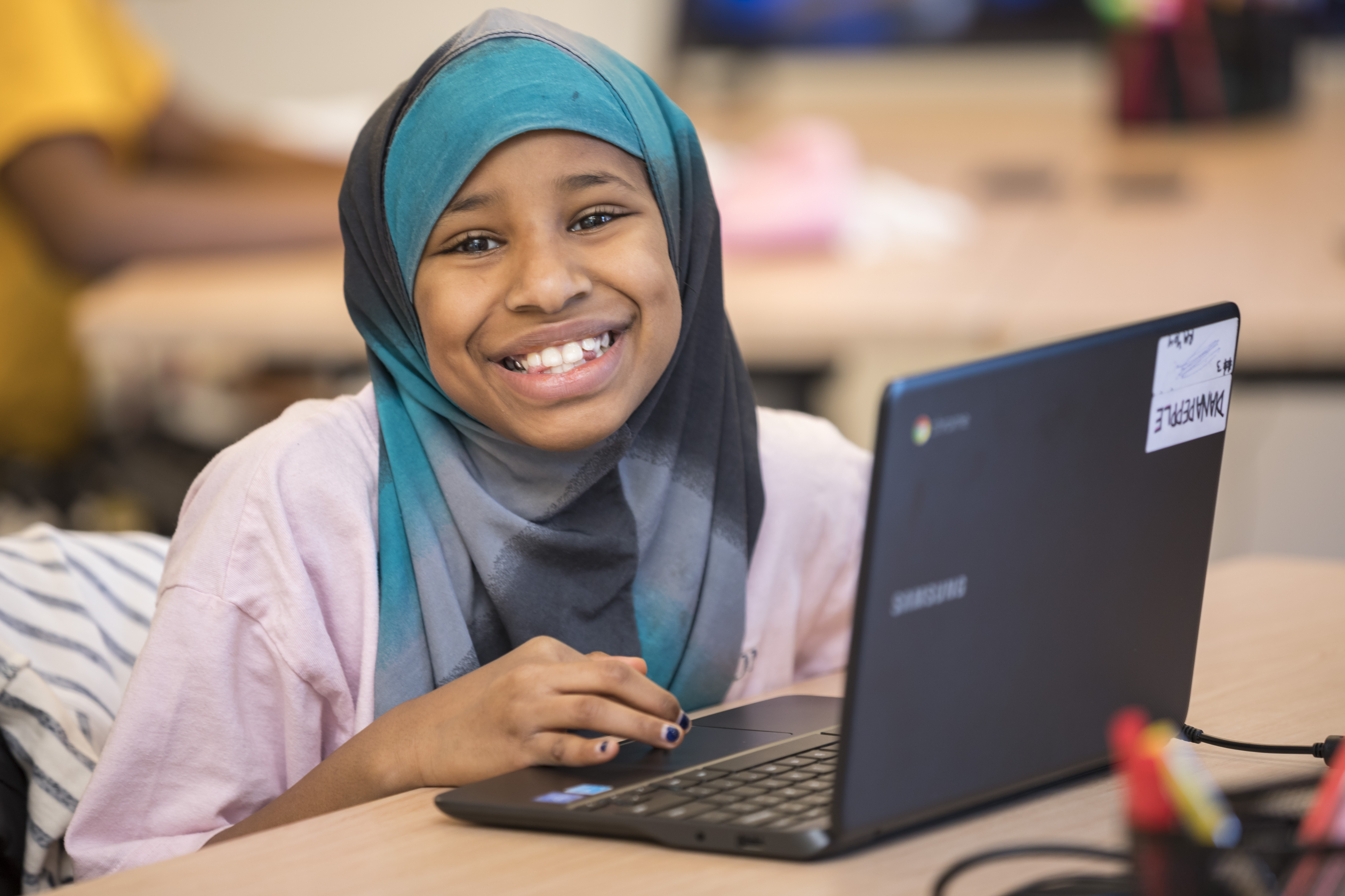 young girl smiles while working on a computer