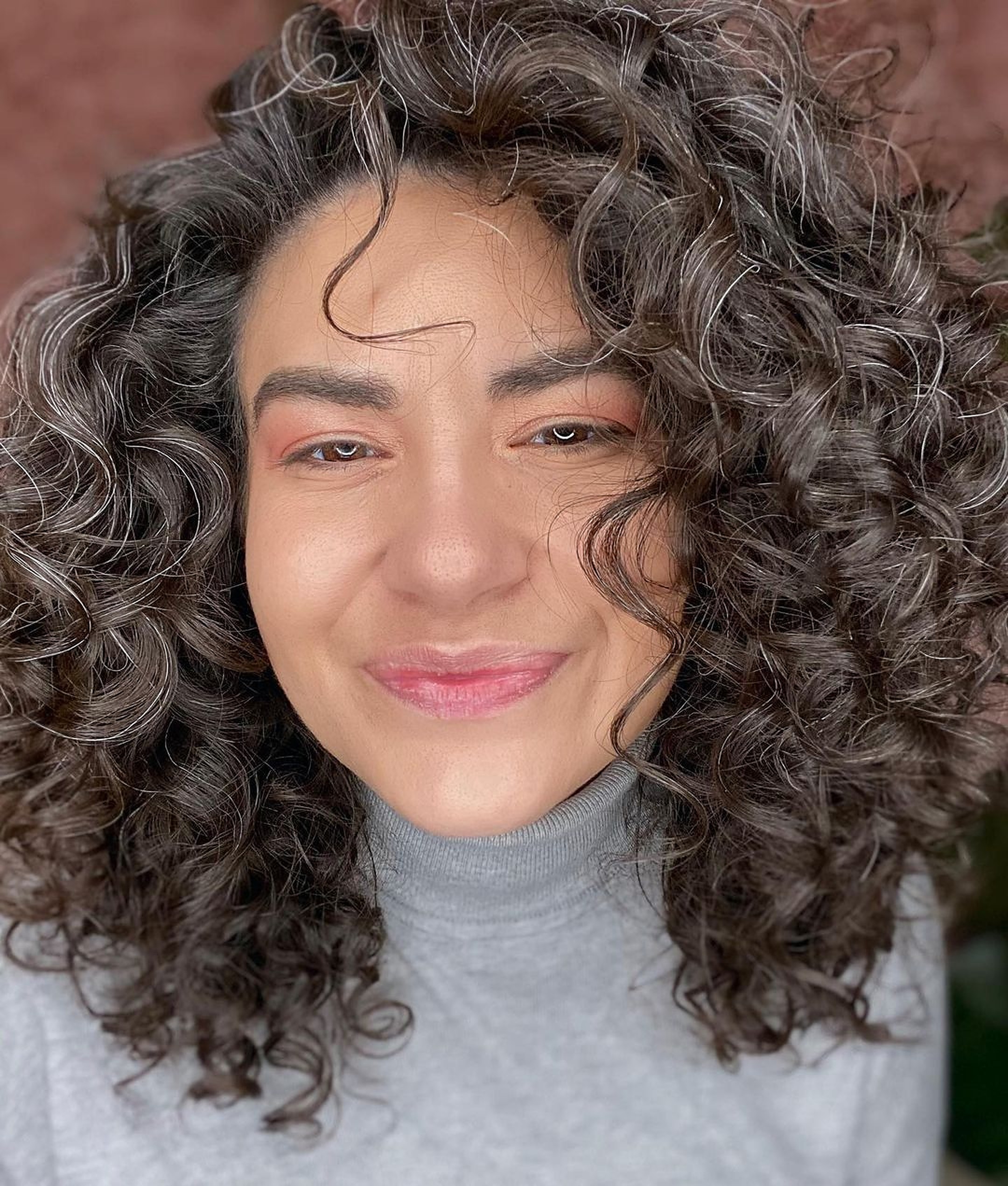 woman with dark curly hair with a few grey hairs