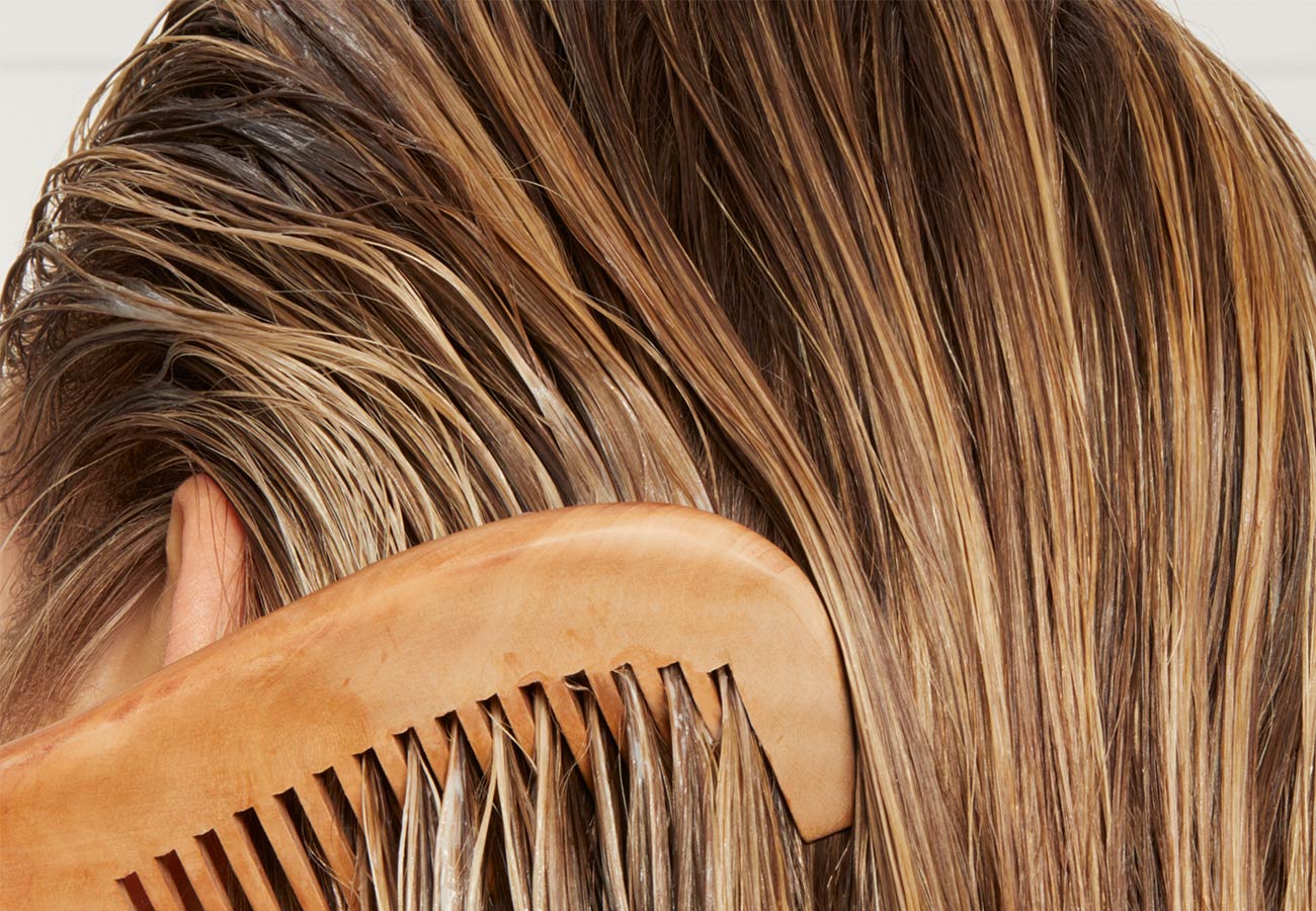 woman with blonde hair runs a comb through her hair