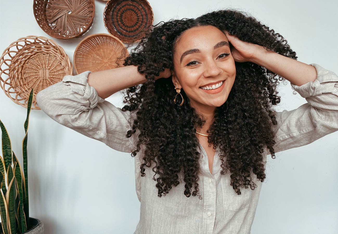 woman with long, brown curly hair smiles