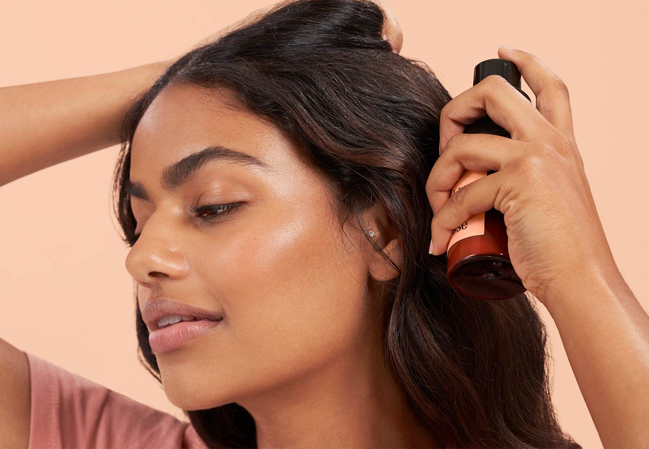 woman with long, dark hair using dry shampoo