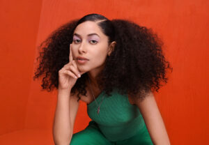woman with curly hair posing with her head rested on her hand