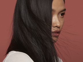 Woman posing with hair being blown in front of her face.