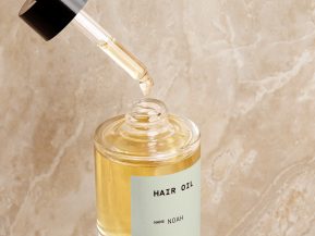 Custom hair oil in front of a marbled blush background