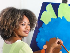 Reyna Noriega poses in front of one of her paintings