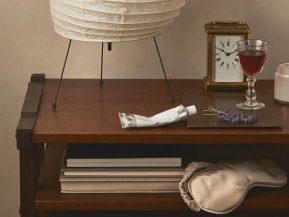 nightstand with eye mask, night cream, clock, and lamp