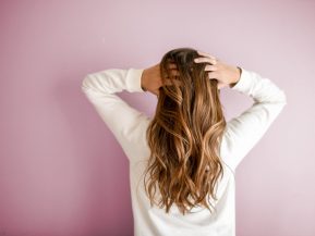 Woman with long brunette hair holding her head