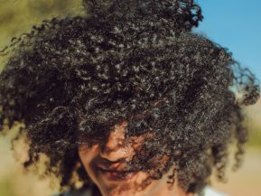 Girl with curly, textured hair with her hair blowing in her face