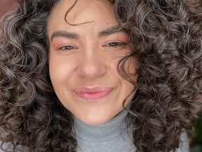 woman with dark curly hair with a few grey hairs