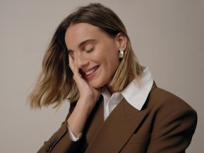 woman with short, brown blowout hair smiles into her palm